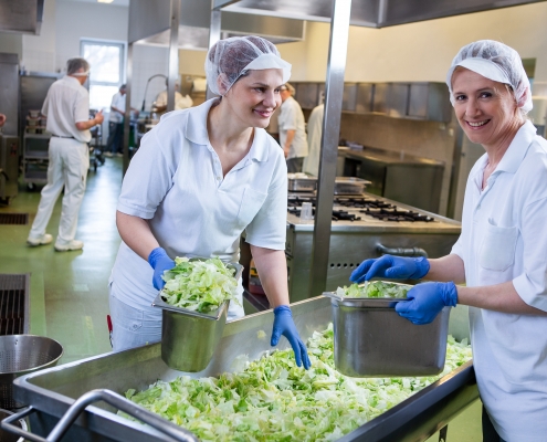 Küchenangestellte in der Großküche beim Salatvorbereiten