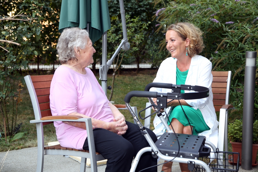 Ältere Dame im Gespräch mit Pflegerin im Garten