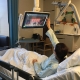 Bettlägrige Patientin bedient Fernsehmonitor am Krankenhausbett