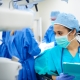 Junge Ärztin in OP-Kleidung hält Klemmbord in der Hand