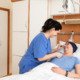 Pflegeperson richtet kranker Patientin Beatmungsschlauch