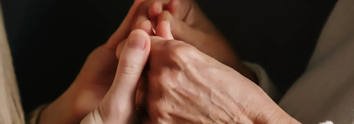 Person hält die Hand einer älteren Dame