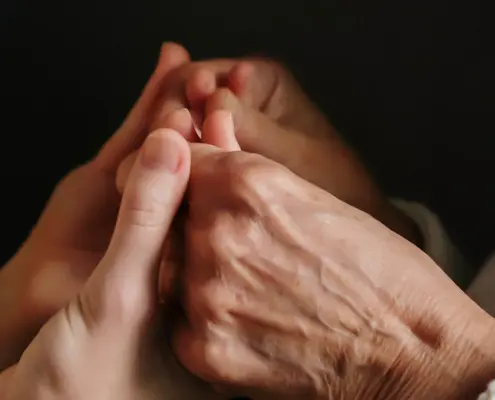 Person hält die Hand einer älteren Dame